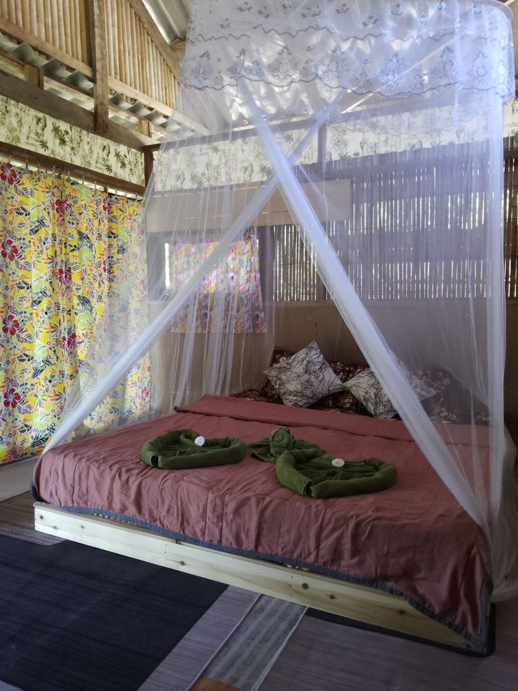 Bed with lace mosquito net and bamboo walls